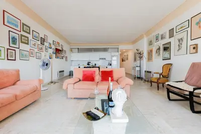 a living room with two pink couches and a kitchen at Una Rosa Blu YourHostHelper in Cannes