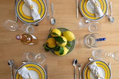 a table with yellow and blue plates and a bowl of fruit at Cannes Suquet Sea View & Beach Access in Cannes