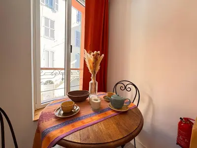 a wooden table with plates and cups and a window at Casa Bisou Cannes - BOHEME in Cannes
