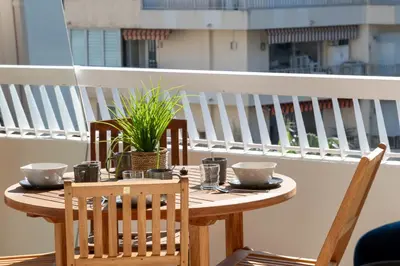 a wooden table with two chairs and a plant on a balcony at Spacious 1-Br Apartment with Terrace Heart of Cannes in Cannes