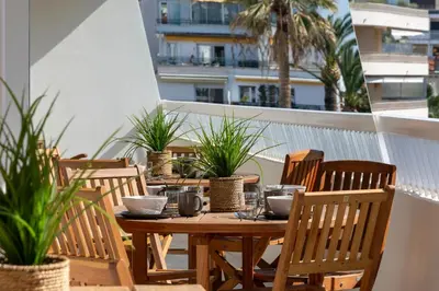 a wooden table and chairs on a balcony with plants at Spacious 1-Br Apartment with Terrace Heart of Cannes in Cannes