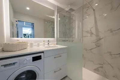a white bathroom with a washing machine and a shower at Spacious 1-Br Apartment with Terrace Heart of Cannes in Cannes