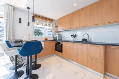 a kitchen with wooden cabinets and a blue chair at Spacious 1-Br Apartment with Terrace Heart of Cannes in Cannes