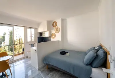 a kitchen with white cabinets and blue tiles on the wall at L'Astrolabe - Studio - refurbished - seaside in Cannes