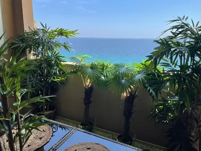 a view of the ocean from a balcony with palm trees at BY NEPTUNE - La Palme Azur Beach view in Cannes