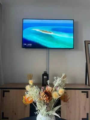 a flat screen tv on a wall with a vase of flowers at BY NEPTUNE - La Palme Azur Beach view in Cannes