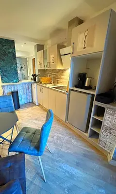 a large kitchen with a blue chair and a table at Charmant Studio - Centre Cannes in Cannes