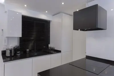 a white kitchen with a black counter and a window at Croisette Star - Bd Croisette in Cannes