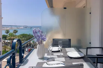 a table with a vase of purple flowers on a balcony at Croisette Star - Bd Croisette in Cannes