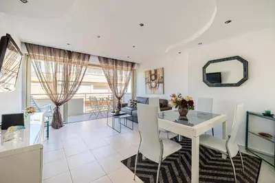 a dining room and living room with a table and chairs at Latour Maubourg 20 by Halldis in Cannes