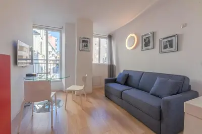 a living room with a blue couch and a glass table at Cannes Serenity – Elegant Stay in Central Cannes in Cannes