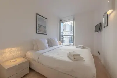 a white bedroom with a large bed and a window at Cannes Serenity – Elegant Stay in Central Cannes in Cannes