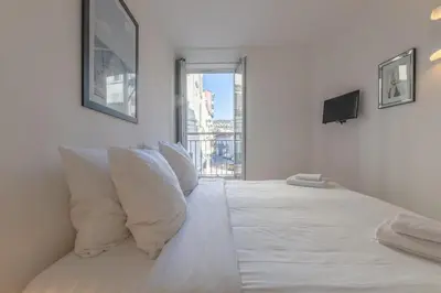 a white bedroom with a bed with pillows and a window at Cannes Serenity – Elegant Stay in Central Cannes in Cannes
