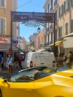a yellow car driving down a city street with a sign at Elegant 2P Rue Meynadier 350 m Palais & beaches in Cannes