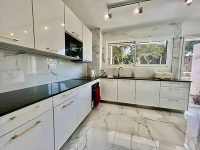 a kitchen with white cabinets and a marble floor at 90 m2, 5 min walk to Croisette, Basse Californie in Cannes