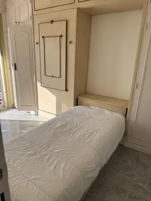 a white bed in a room with a cabinet at Central location, terrace, 2 bedrooms in Cannes