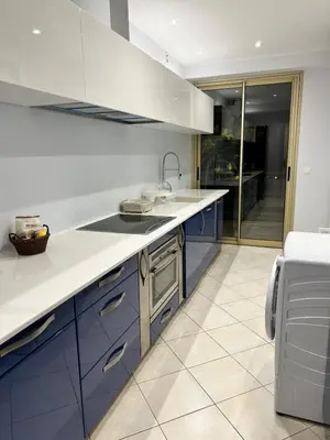 a kitchen with white counters and blue cabinets at Cannes Blue Riviera Luxe in Cannes