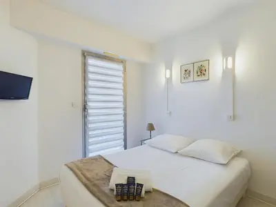 a white bedroom with a bed and a window at Centre Cannes Suquet in Cannes