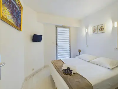 a white bedroom with a bed and a window at Centre Cannes Suquet in Cannes