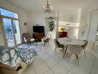 a living room with a table and chairs and a television at Cannes Croisette - 2 pièces vue mer in Cannes