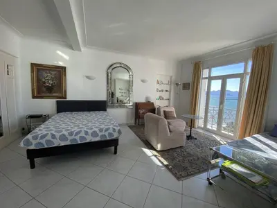 a bedroom with a bed and a chair and a mirror at Cannes Croisette - 2 pièces vue mer in Cannes