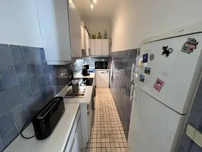 a small kitchen with a white refrigerator and a tile floor at Cannes Croisette - 2 pièces vue mer in Cannes