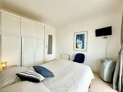 a bedroom with a bed and a blue chair at Nice 1 bedroom, sea view, 10 min from Cannes Center & Palais des Festivals in Cannes