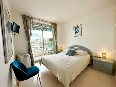 a bedroom with a bed and a chair and a window at Nice 1 bedroom, sea view, 10 min from Cannes Center & Palais des Festivals in Cannes
