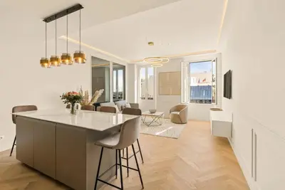 a kitchen and living room with a counter and chairs at LES SUITES DU PALAIS sur LA CROISETTE - Vue MER in Cannes