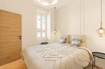 a white bedroom with a bed and a window at LES SUITES DU PALAIS sur LA CROISETTE - Vue MER in Cannes