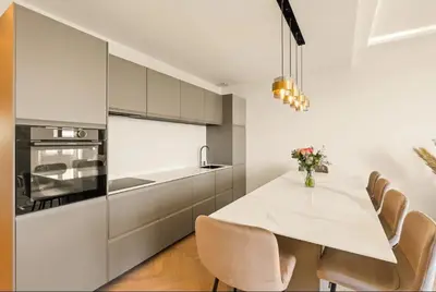 a white kitchen with a white table and chairs at LES SUITES DU PALAIS sur LA CROISETTE - Vue MER in Cannes
