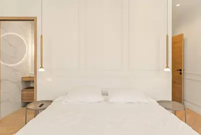 a white bed in a room with two tables at LES SUITES DU PALAIS sur LA CROISETTE - Vue MER in Cannes