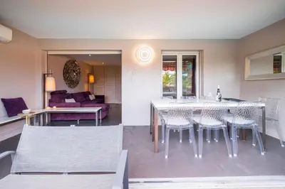 a dining room and living room with a table and chairs at Cannes plage - avec terrasse, vue, mer, piscine, plage, garage in Cannes