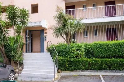 a pink building with stairs and trees in front of it at Cannes plage - avec terrasse, vue, mer, piscine, plage, garage in Cannes