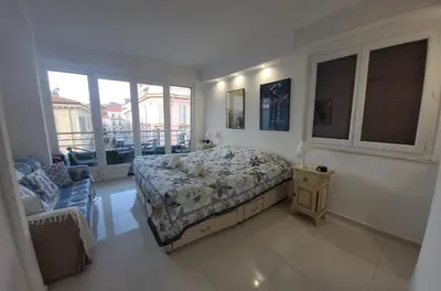 a bedroom with a bed and a chair and windows at Center Cannes Hippocampe in Cannes