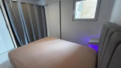 a bedroom with a bed and a window with a purple light at La Pitchounette bord de mer in Cannes
