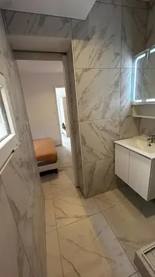 a bathroom with a sink and a marble wall at La Pitchounette bord de mer in Cannes