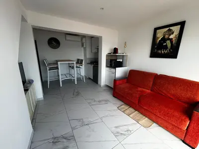 a living room with a red couch and a kitchen at La Pitchounette bord de mer in Cannes