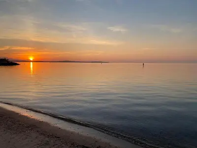 a sunset over the water with a beach at La Pitchounette bord de mer in Cannes