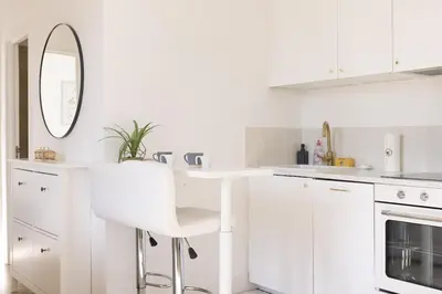 a white kitchen with a white counter and a stool at Astéria - cosy, moderne, clim, 15mn Palais&Plages in Cannes