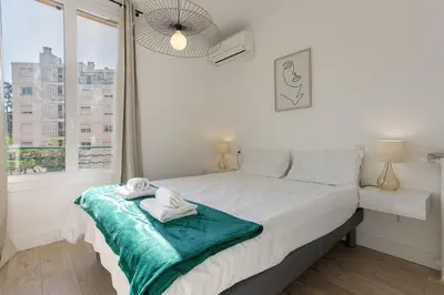 a white bedroom with a bed with towels on it at Astéria - cosy, moderne, clim, 15mn Palais&Plages in Cannes