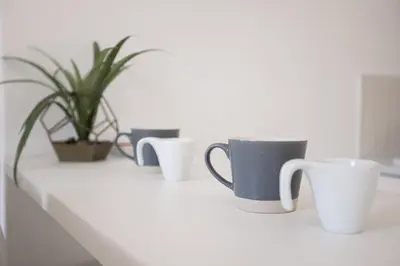 four coffee cups and a potted plant on a counter at Astéria - cosy, moderne, clim, 15mn Palais&Plages in Cannes