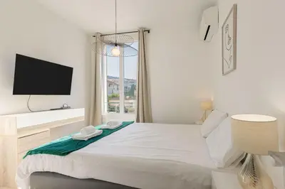 a white bedroom with a large bed with a flat screen tv at Astéria - cosy, moderne, clim, 15mn Palais&Plages in Cannes