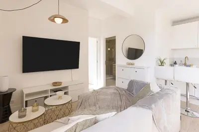 a living room with a couch and a tv on a wall at Astéria - cosy, moderne, clim, 15mn Palais&Plages in Cannes