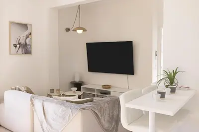 a living room with a couch and a tv on a wall at Astéria - cosy, moderne, clim, 15mn Palais&Plages in Cannes