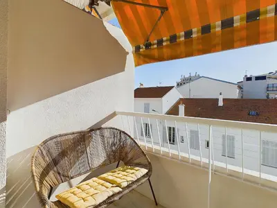 a rattan chair sitting on a balcony with a view at Center Cannes Montfleury in Cannes
