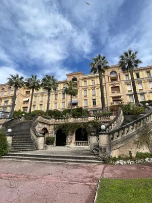 a large building with palm trees in front of it at Parc Continental Apartment with sea view in Cannes