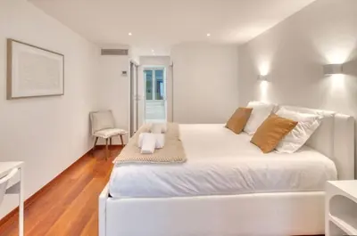 a white bedroom with a large bed and a chair at Cannes 50m palais & Croisette in Cannes
