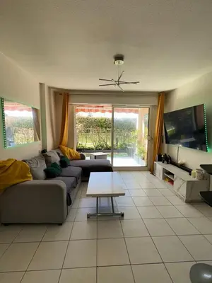 a living room with a couch and a table at 2P jardin Sud vue Lac avec piscine tennis parking privé in Le Cannet