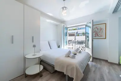 a white bedroom with a bed and a window at Bright Apartment in the Heart of Cannes in Cannes